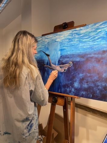 Artist Nikolina Kovalenko working on her painting "Underwater Dreamer - Self Portrait as a Free Diver" at Caldwell Gallery Hudson.
